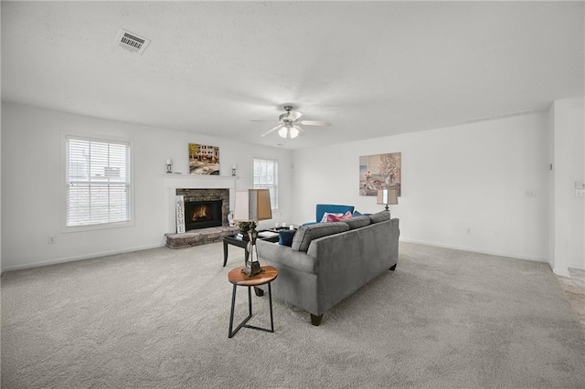 carpeted living room with a fireplace, visible vents, baseboards, and a ceiling fan