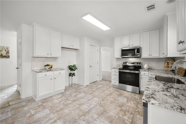 kitchen featuring a sink, visible vents, appliances with stainless steel finishes, and light stone countertops