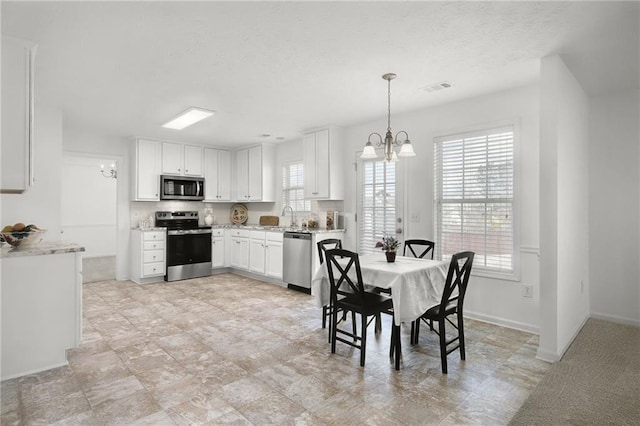 dining area featuring a chandelier, a textured ceiling, baseboards, and visible vents