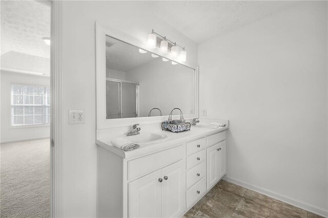 bathroom featuring baseboards, double vanity, a textured ceiling, and a sink