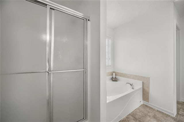 full bathroom with a shower stall, baseboards, and a garden tub