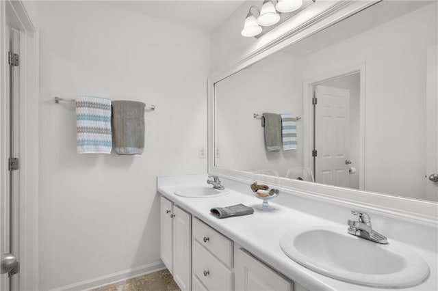 bathroom with double vanity, a sink, and baseboards