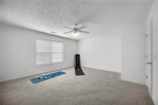 workout room with a textured ceiling, ceiling fan, baseboards, and carpet floors