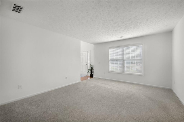 carpeted spare room with a textured ceiling, baseboards, and visible vents