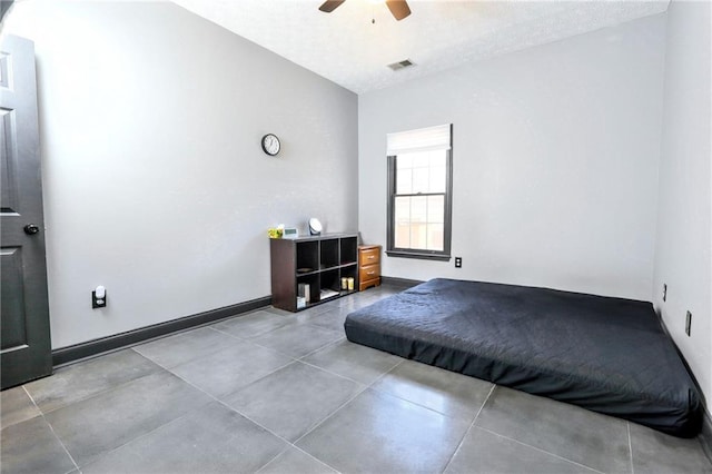 bedroom featuring baseboards, a textured ceiling, visible vents, and a ceiling fan