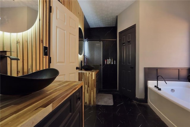 full bathroom featuring marble finish floor, a stall shower, a textured ceiling, vanity, and a bath