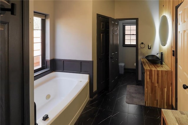 full bathroom with toilet, plenty of natural light, vanity, and a bath