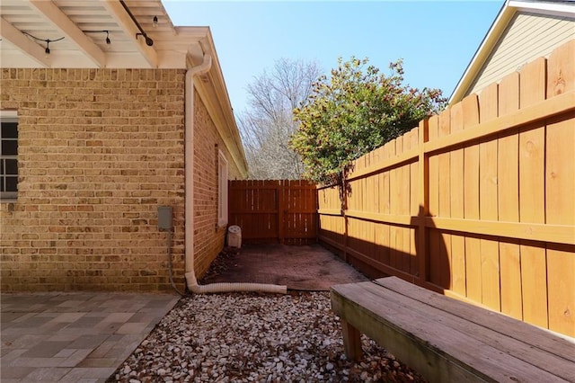 view of side of property with a patio area, brick siding, and a fenced backyard