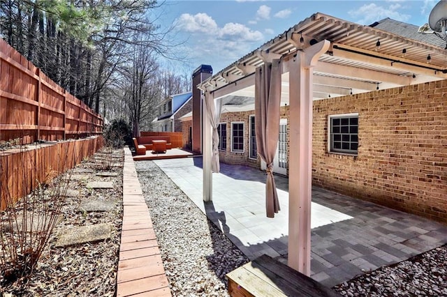 exterior space featuring a patio area, fence, a pergola, and brick siding