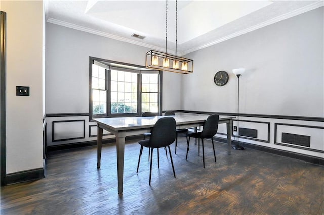 dining room featuring ornamental molding, visible vents, a decorative wall, and wood finished floors