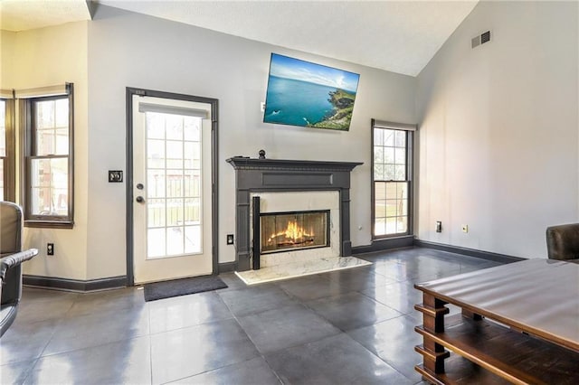 living room featuring high vaulted ceiling, a premium fireplace, visible vents, and baseboards