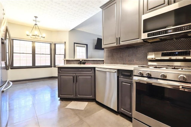 kitchen featuring a notable chandelier, light countertops, backsplash, appliances with stainless steel finishes, and a textured ceiling