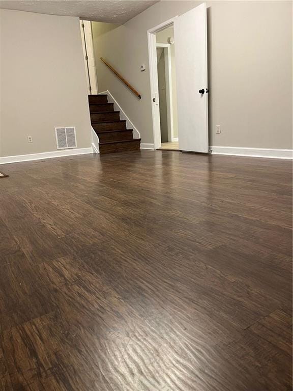 unfurnished room with a textured ceiling and dark wood-type flooring