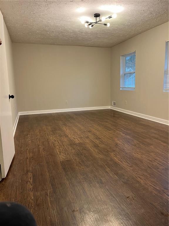 unfurnished room with dark hardwood / wood-style flooring and a textured ceiling