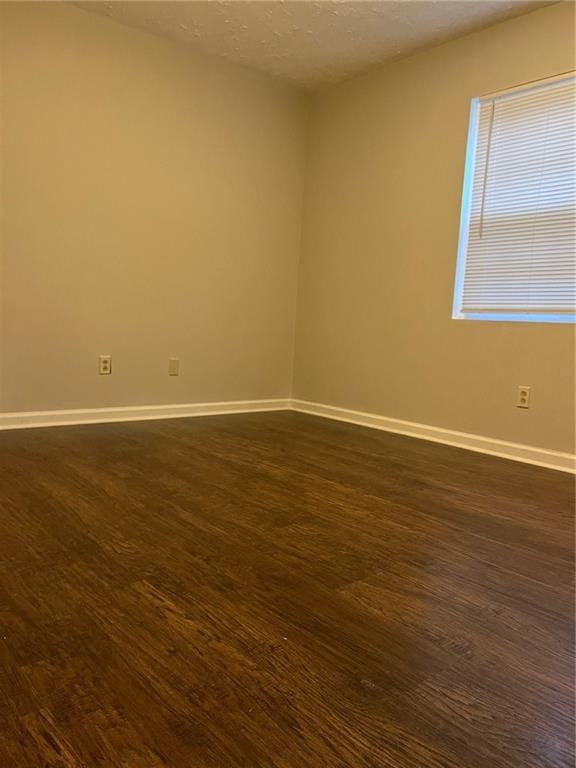 unfurnished room featuring dark wood-type flooring and a textured ceiling