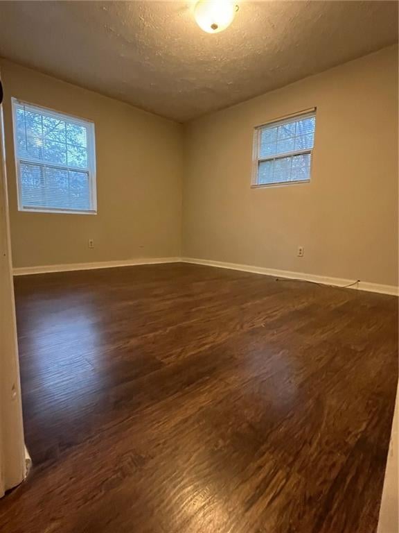 spare room featuring a textured ceiling and dark wood-type flooring