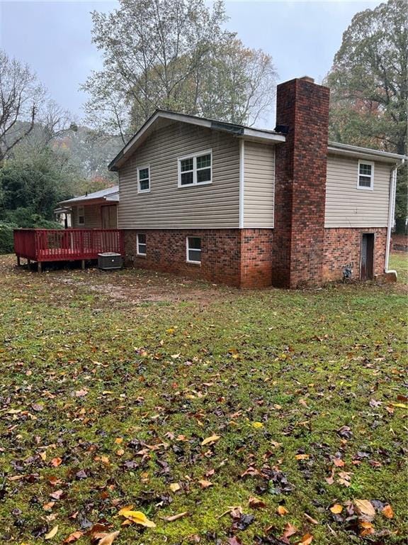 view of side of property with central AC, a lawn, and a wooden deck