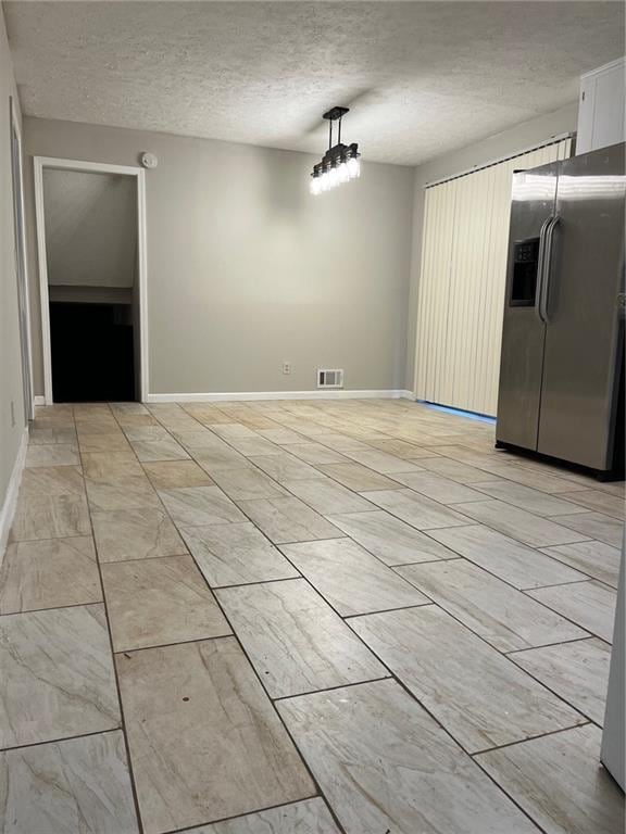 unfurnished dining area featuring a textured ceiling