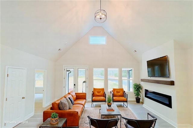 living area featuring high vaulted ceiling, baseboards, french doors, light wood-type flooring, and a glass covered fireplace