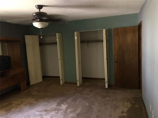 unfurnished bedroom featuring multiple closets, carpet flooring, a ceiling fan, baseboards, and a textured ceiling