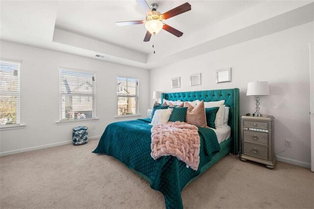 bedroom featuring a tray ceiling, multiple windows, and ceiling fan