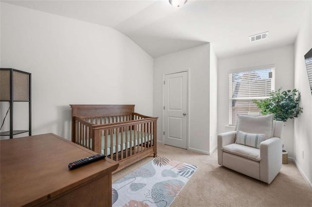 carpeted bedroom with vaulted ceiling and a nursery area