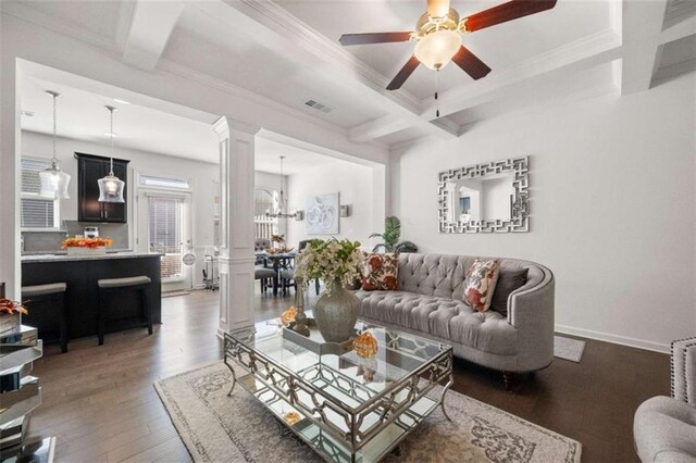 living room featuring dark wood-type flooring, coffered ceiling, ceiling fan with notable chandelier, ornamental molding, and beam ceiling