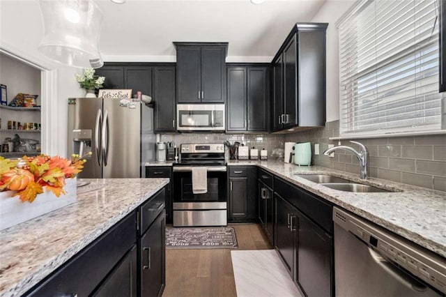 kitchen featuring light stone countertops, stainless steel appliances, sink, decorative light fixtures, and dark hardwood / wood-style floors