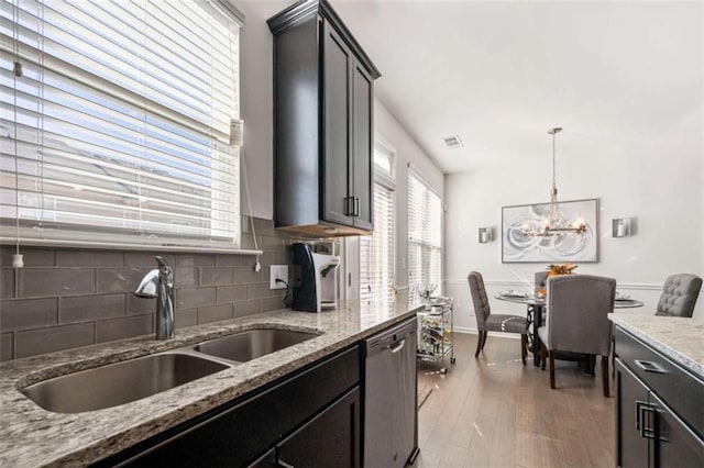 kitchen with sink, an inviting chandelier, stainless steel dishwasher, light hardwood / wood-style floors, and decorative light fixtures