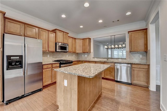 kitchen featuring visible vents, light wood finished floors, ornamental molding, appliances with stainless steel finishes, and a sink