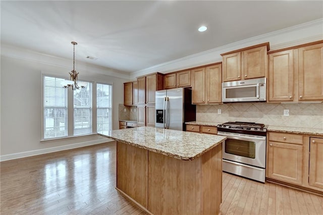 kitchen featuring light wood-style flooring, backsplash, crown molding, appliances with stainless steel finishes, and a center island