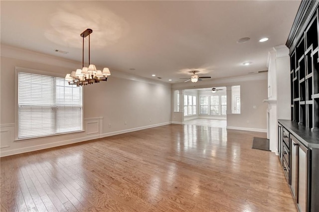 unfurnished living room featuring light wood finished floors, ceiling fan with notable chandelier, and crown molding