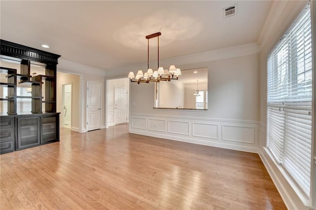 interior space featuring visible vents, a notable chandelier, wood finished floors, and ornamental molding