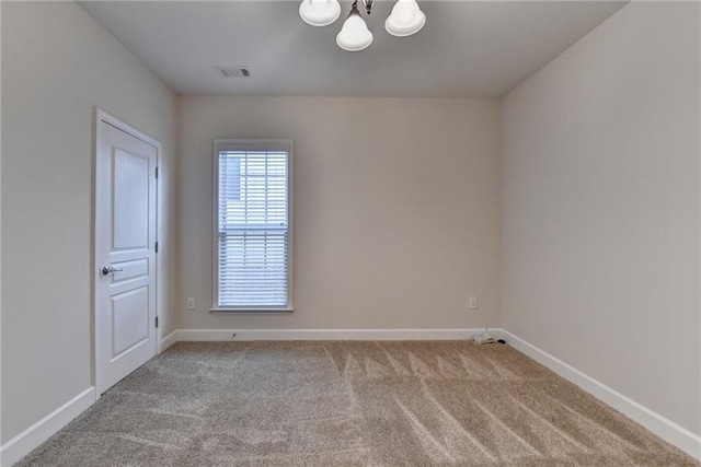 empty room featuring baseboards, a notable chandelier, visible vents, and carpet