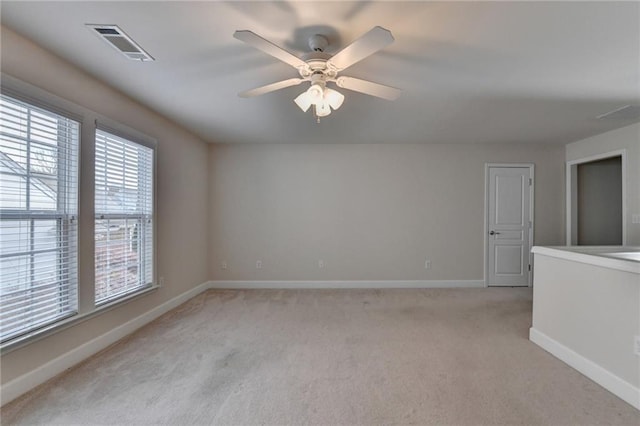 spare room featuring a ceiling fan, light carpet, baseboards, and visible vents