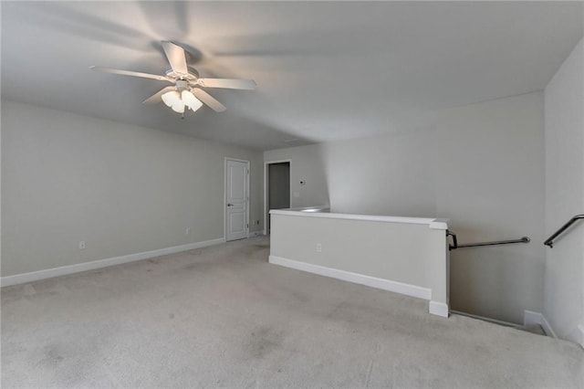 spare room featuring baseboards, a ceiling fan, and light colored carpet