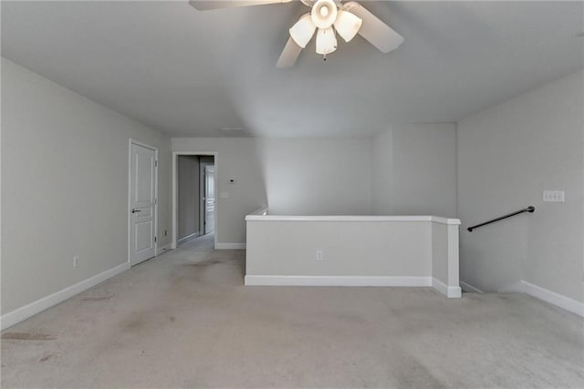 carpeted empty room featuring a ceiling fan and baseboards