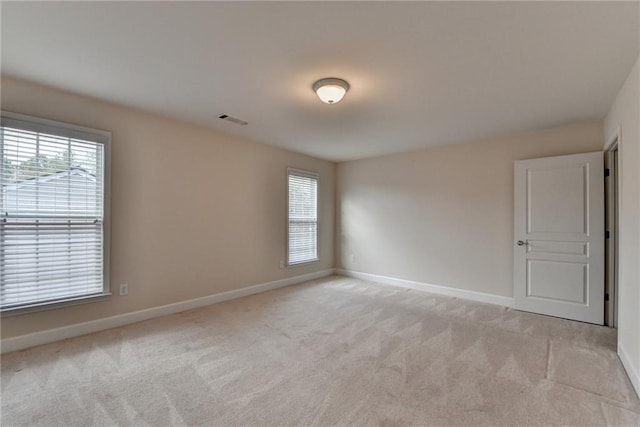unfurnished room featuring a healthy amount of sunlight, light colored carpet, and visible vents