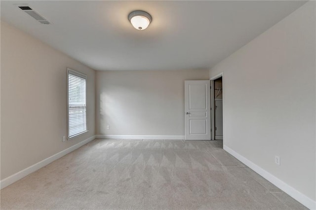 spare room with baseboards, visible vents, and light colored carpet