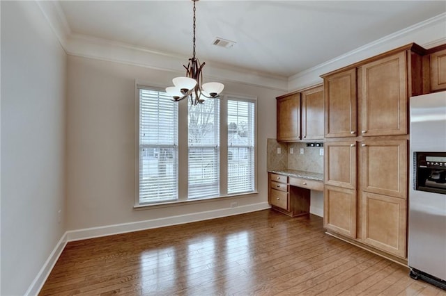 kitchen featuring light wood-style flooring, crown molding, built in desk, stainless steel fridge with ice dispenser, and a notable chandelier