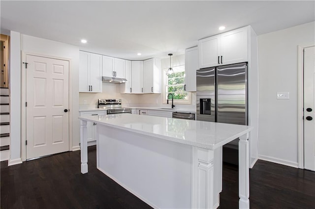 kitchen featuring sink, stainless steel appliances, white cabinets, and hanging light fixtures