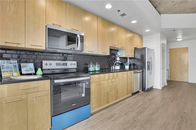 kitchen featuring dark countertops, light brown cabinets, and stainless steel appliances