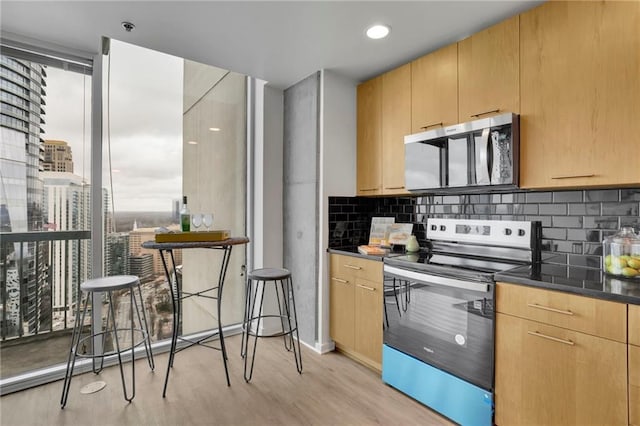 kitchen with stainless steel appliances, light brown cabinets, light wood-style flooring, and tasteful backsplash