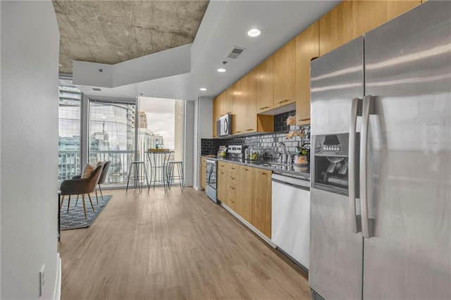 kitchen featuring light wood finished floors, tasteful backsplash, visible vents, dark countertops, and appliances with stainless steel finishes