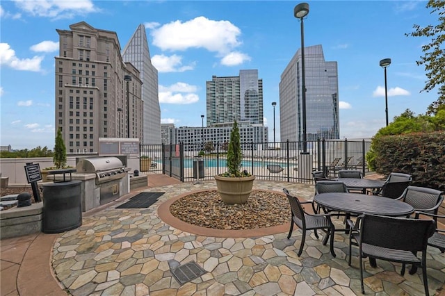 view of patio / terrace with a view of city, fence, a community pool, and area for grilling