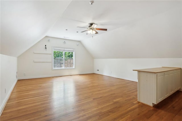 additional living space featuring ceiling fan, vaulted ceiling, and light wood-type flooring