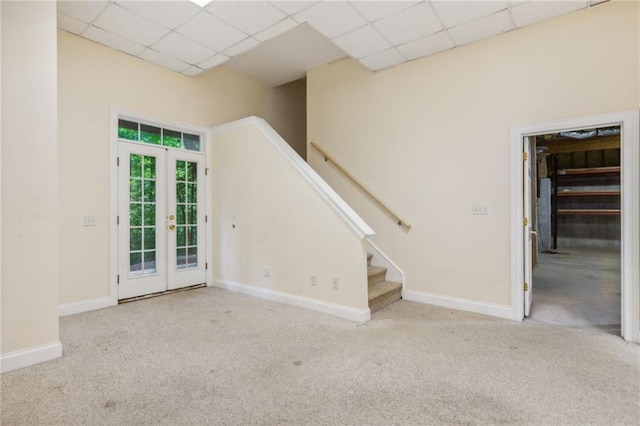 interior space with light carpet, a drop ceiling, and french doors