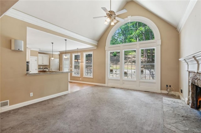 unfurnished living room featuring light carpet, a fireplace, ornamental molding, and ceiling fan