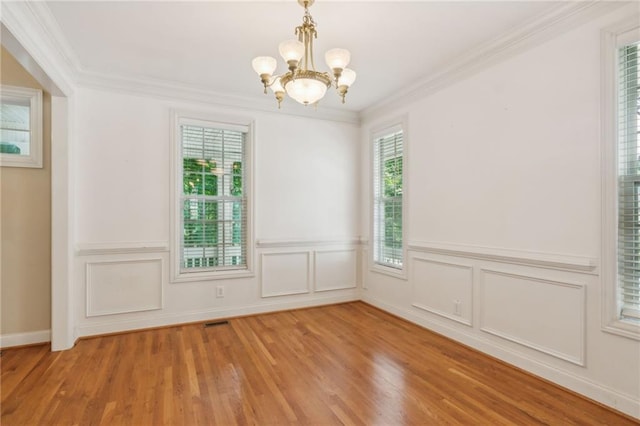 spare room with ornamental molding, a wealth of natural light, and light hardwood / wood-style floors