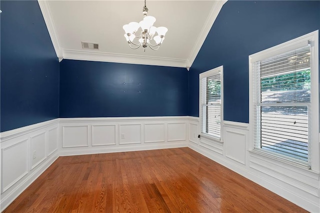 spare room with crown molding, vaulted ceiling, hardwood / wood-style floors, and an inviting chandelier
